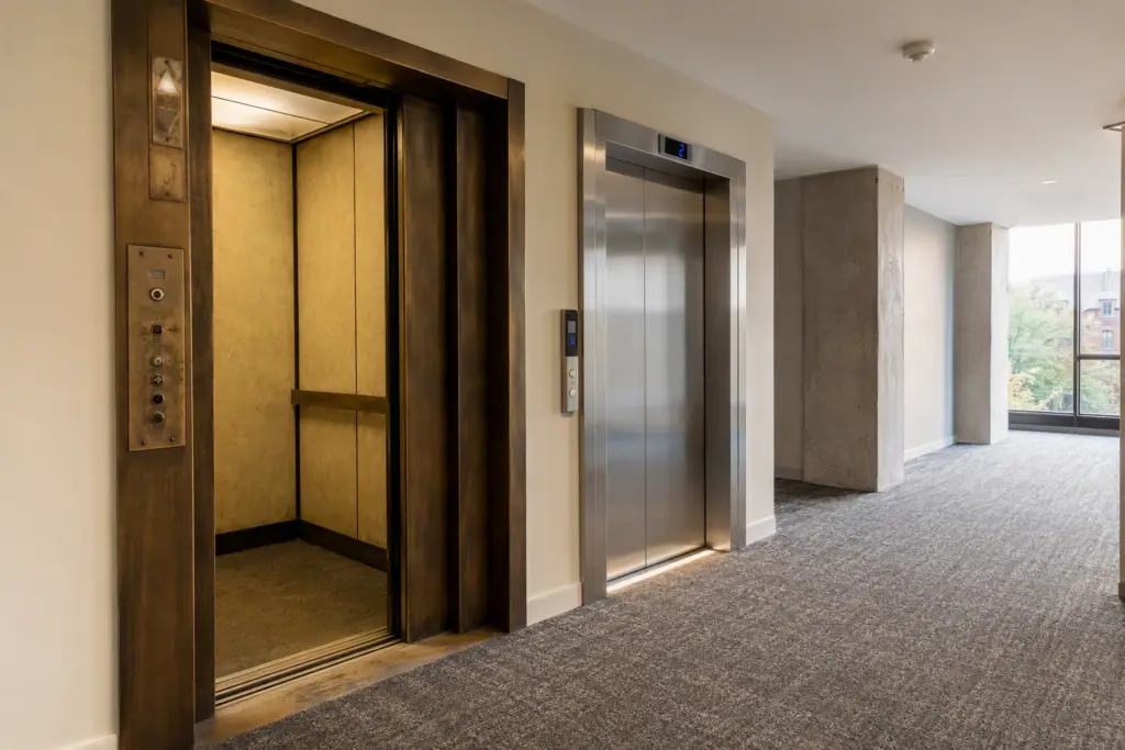 Side-by-side view of an aging elevator and a modernized elevator cab in a Columbia SC office building, illustrating modernization vs replacement cost tradeoffs.
