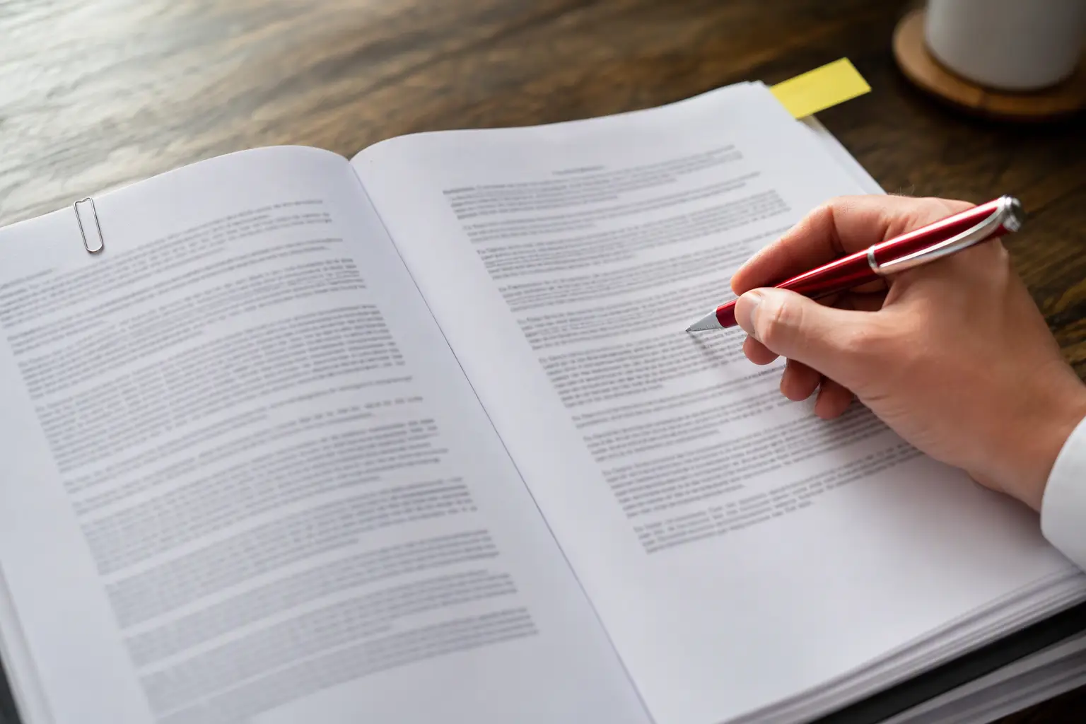 Close-up of a building owner marking an automatic renewal clause in an elevator service agreement with a red pen before signing