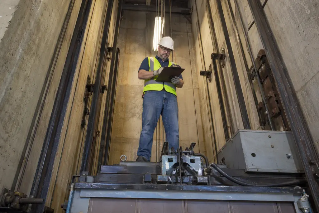 Certified elevator inspector performing a Category 1 load test inspection on an older traction elevator hoistway in a Columbia SC commercial building