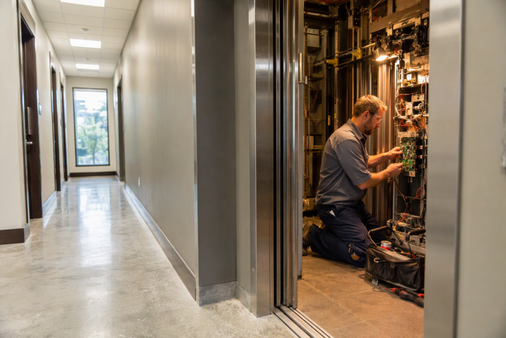 Licensed elevator technician inspecting an open commercial elevator cab during a repair service call at a Columbia SC mid-rise office building