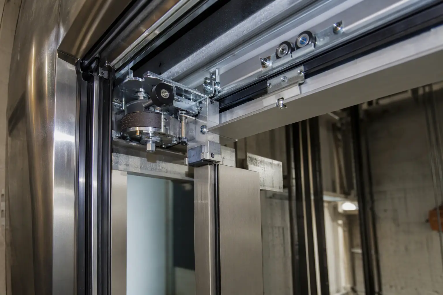 Close-up of a hotel elevator door operator assembly showing new clutch mechanism, safety edge, and roller hardware that reduce unplanned service interruptions in high-traffic hotel environments